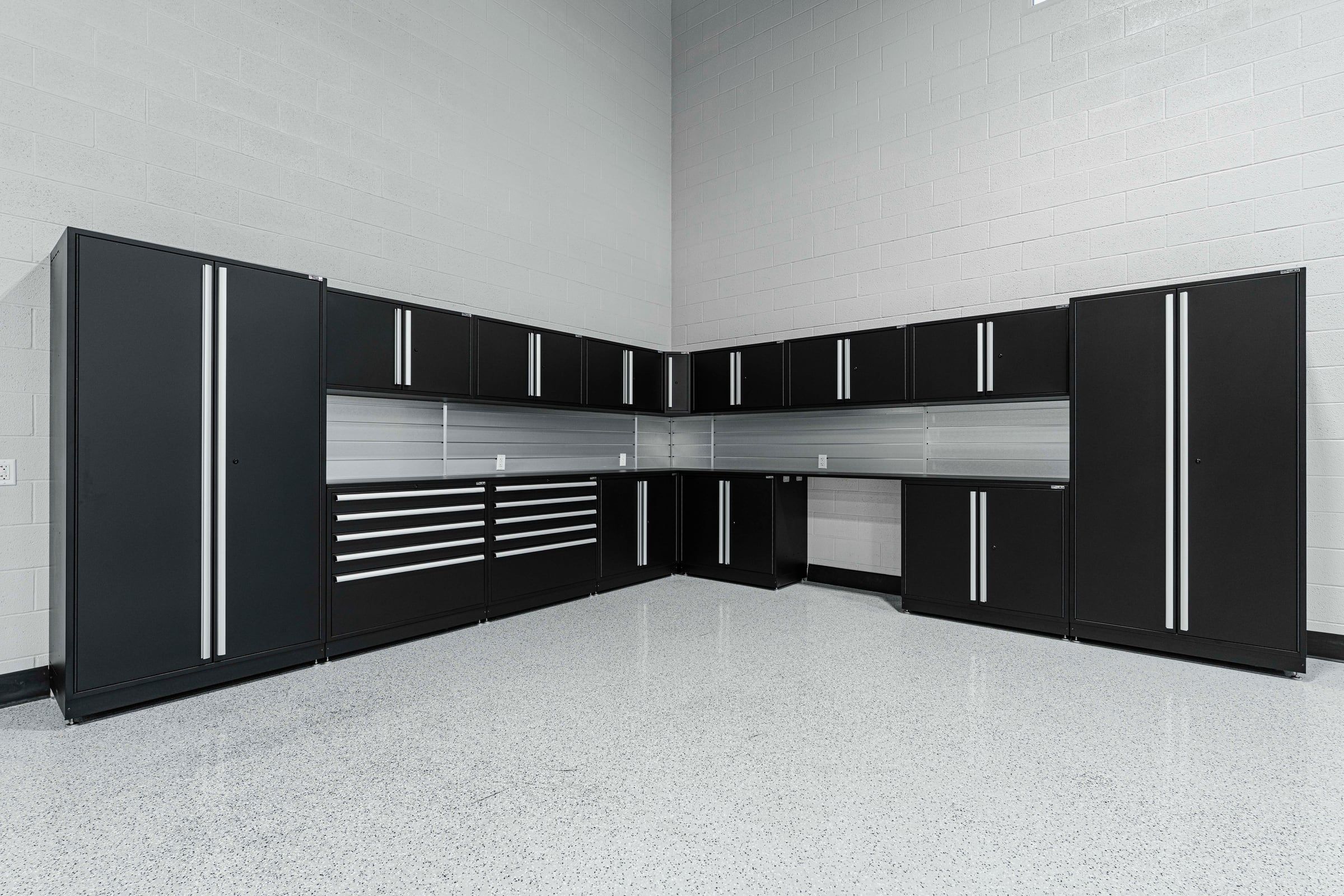 Corner run of black steel cabinets with a stainless worktop under bright lights