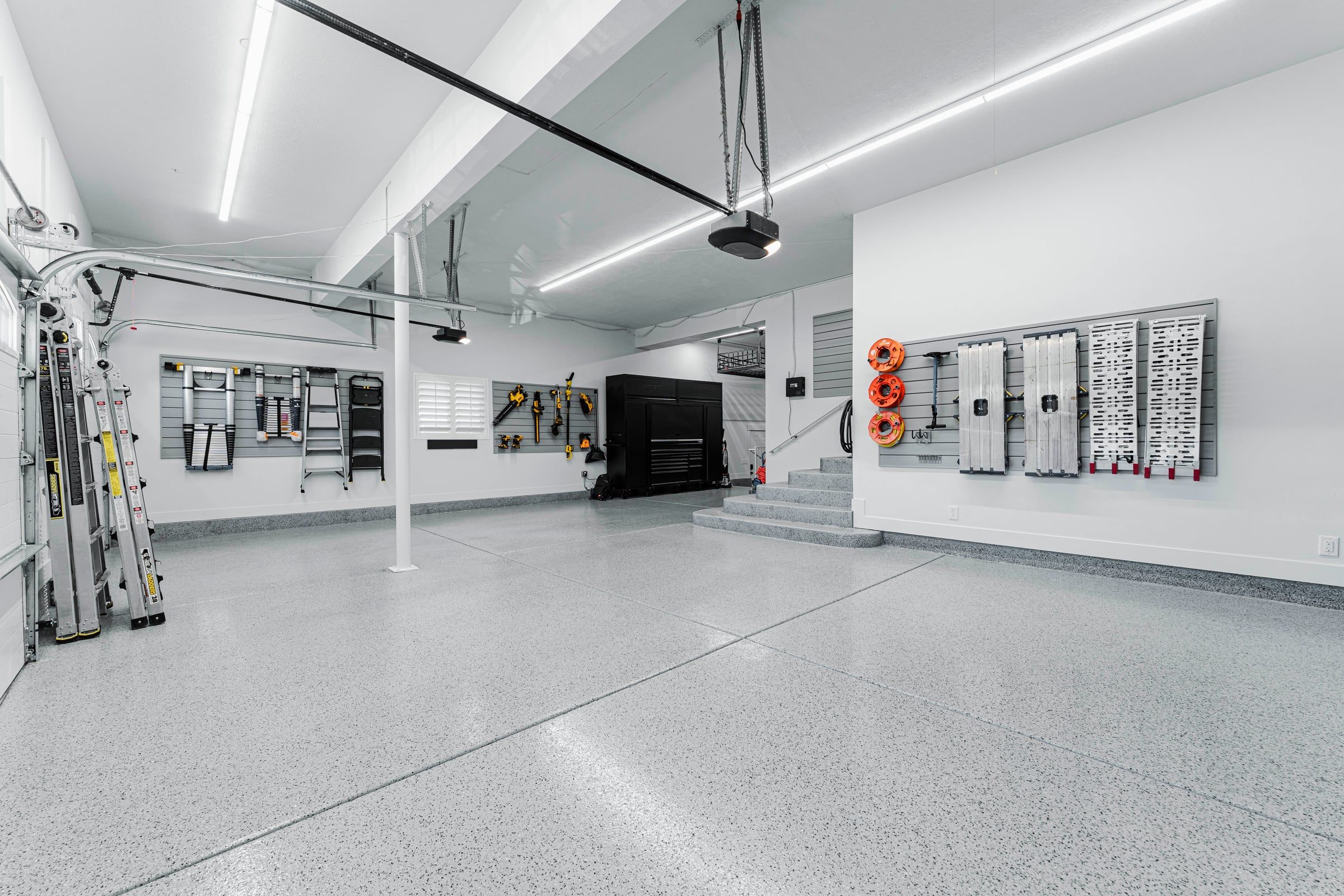 Wide garage with flake floor, slatwall tool storage and bright LED strip lights