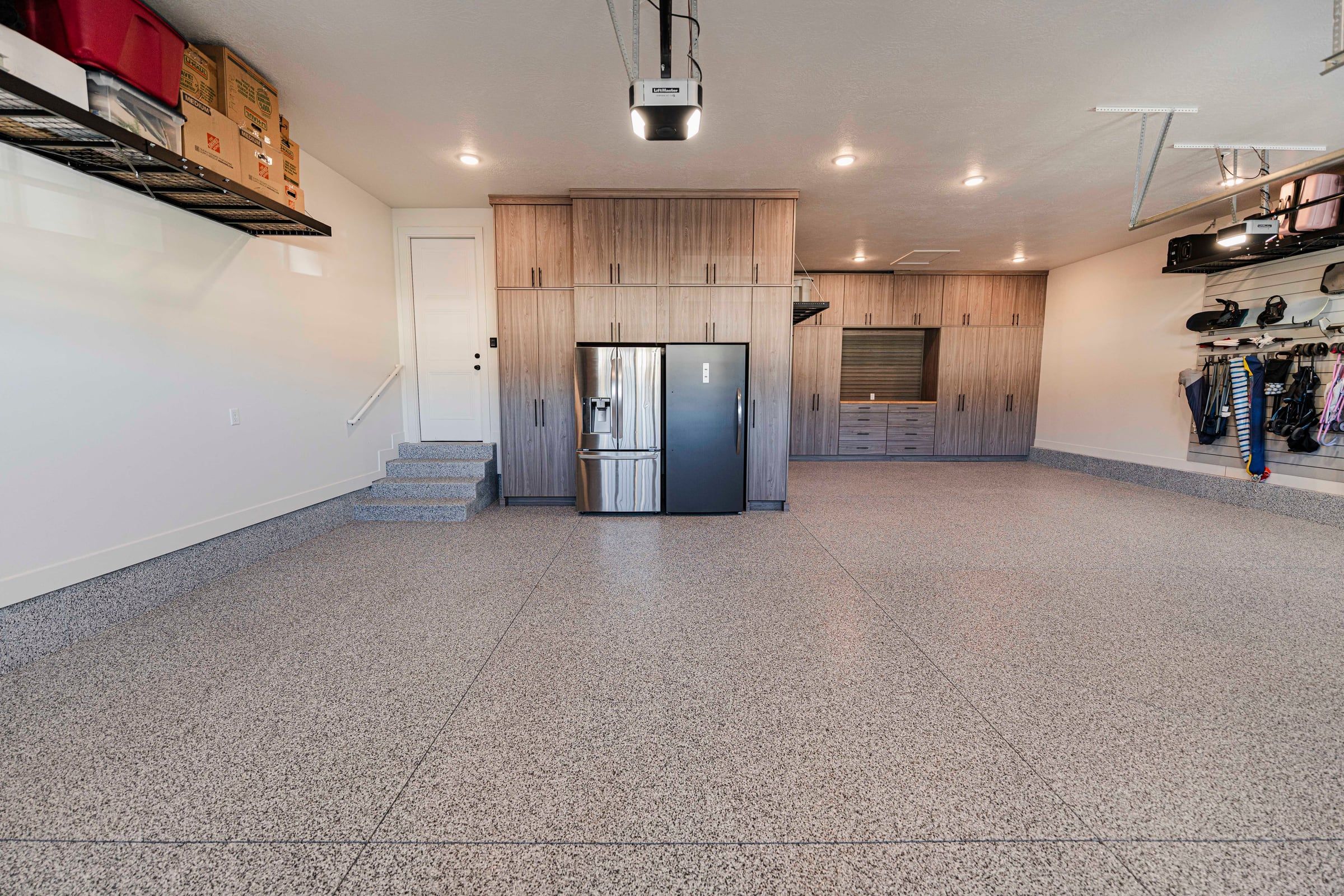Garage with wood-look tall cabinets, overhead racks and a speckled flake floor